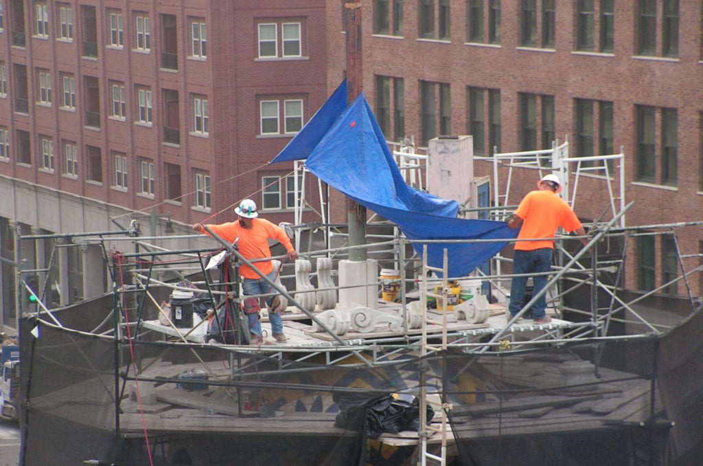 two men in hard hats working on top of the Herald Examiner Building rotunda matt construction