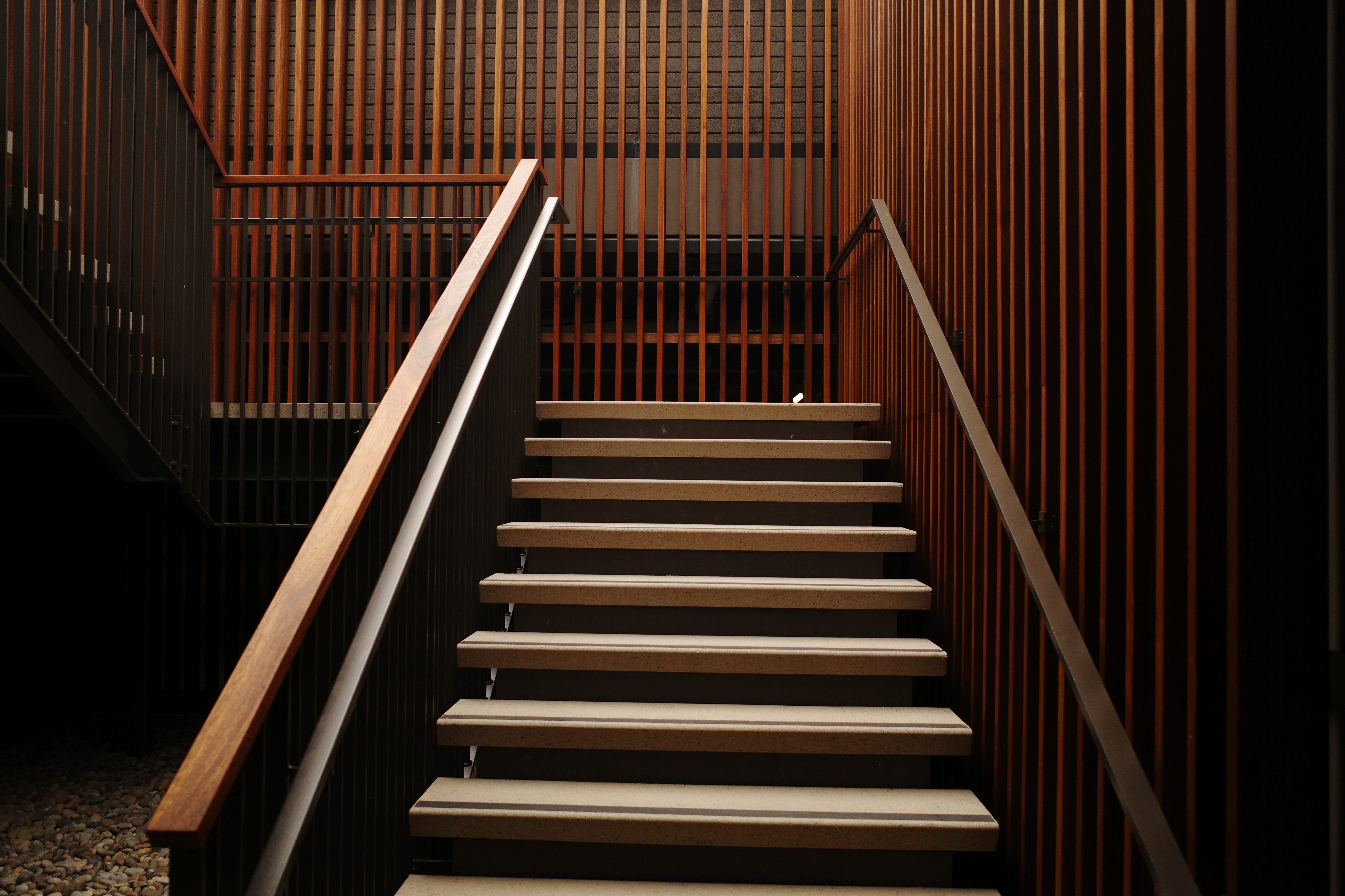 Modern staircase with light wood handrails and stone treads at Cross Creek Ranch.
