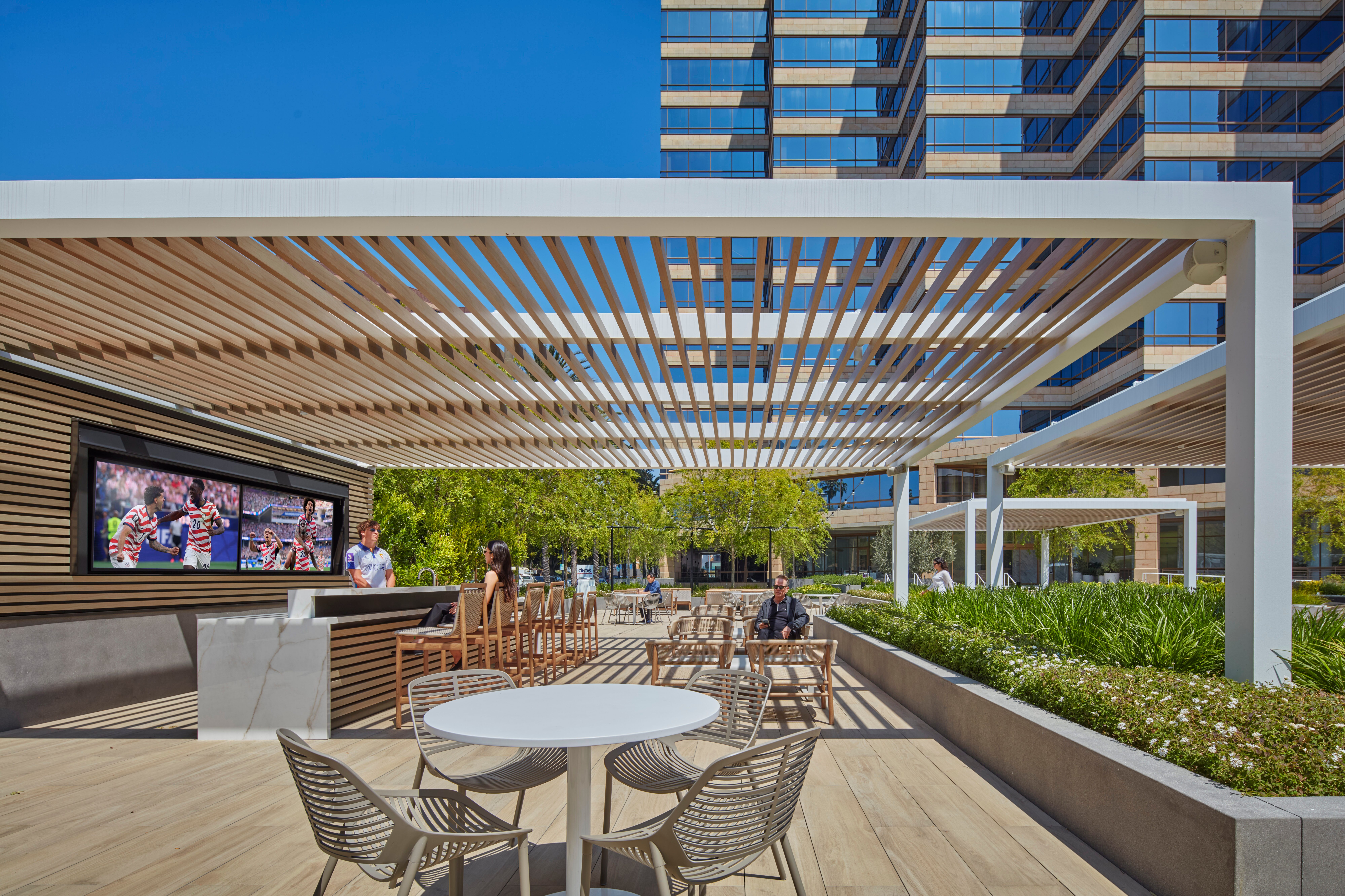 Studio Plaza outdoor lounge with pergola, seating, and TV screens