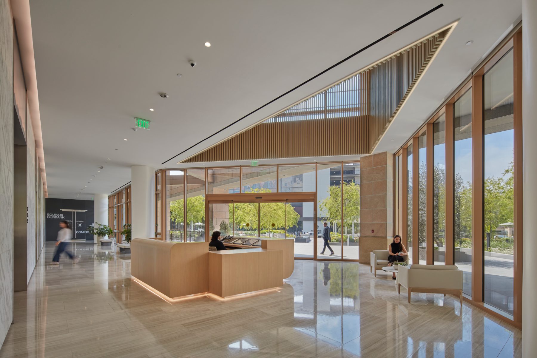 Studio Plaza lobby with wood reception desk, lounge seating, and floor-to-ceiling windows.
