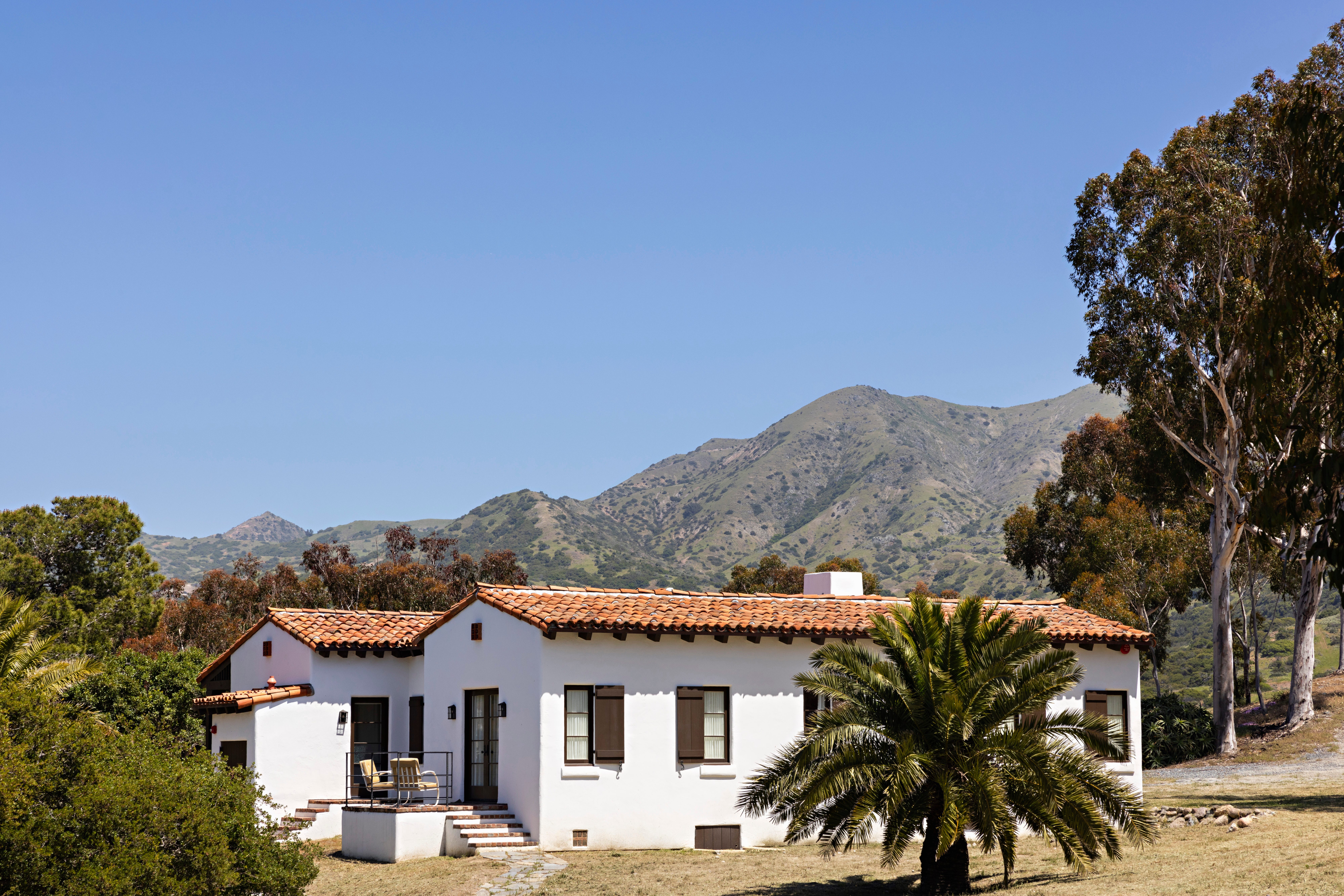 White ranch house with red tile roof set against rugged mountains at El Rancho Escondido