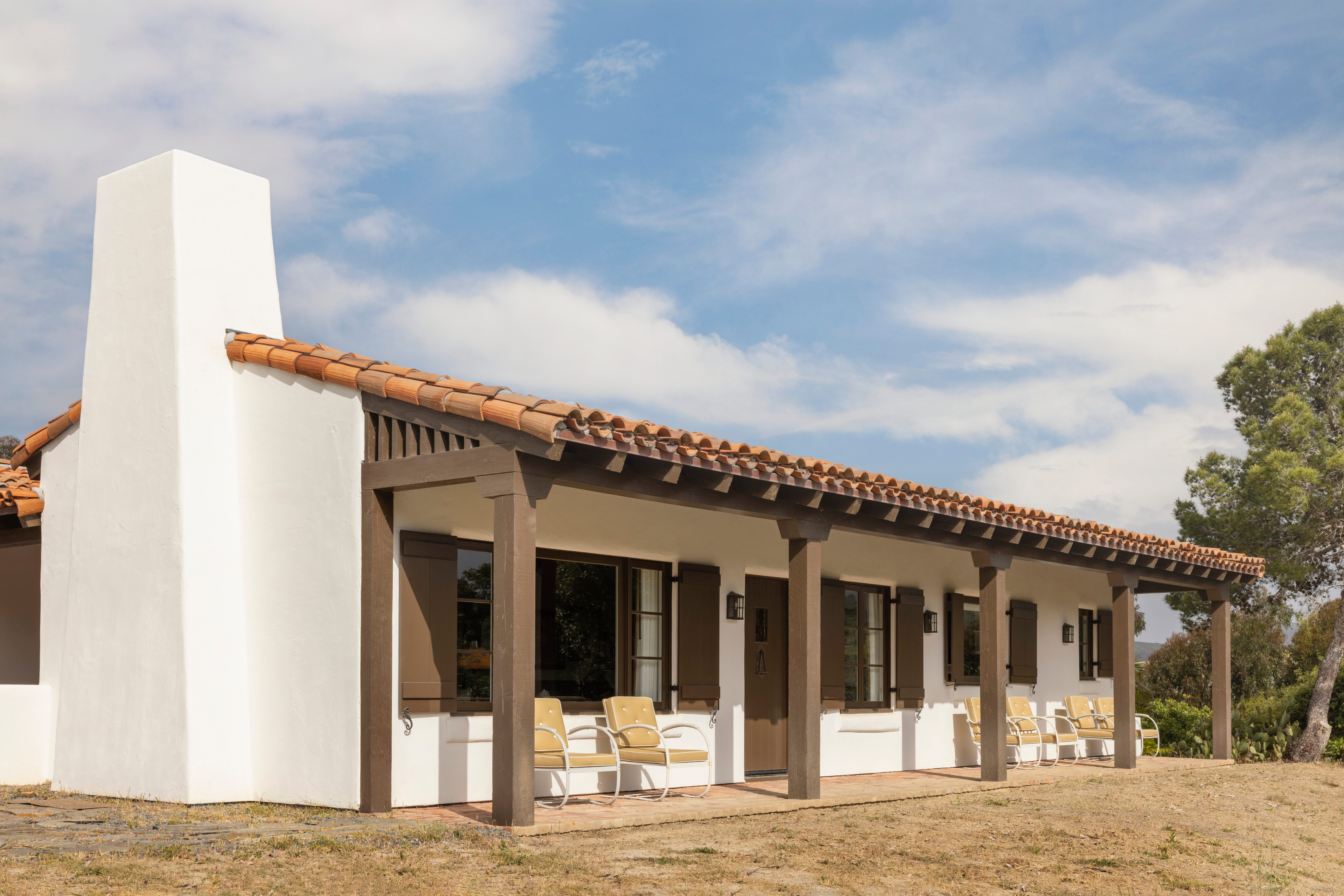 Exterior of a white adobe ranch house with red tile roof at El Rancho Escondido.